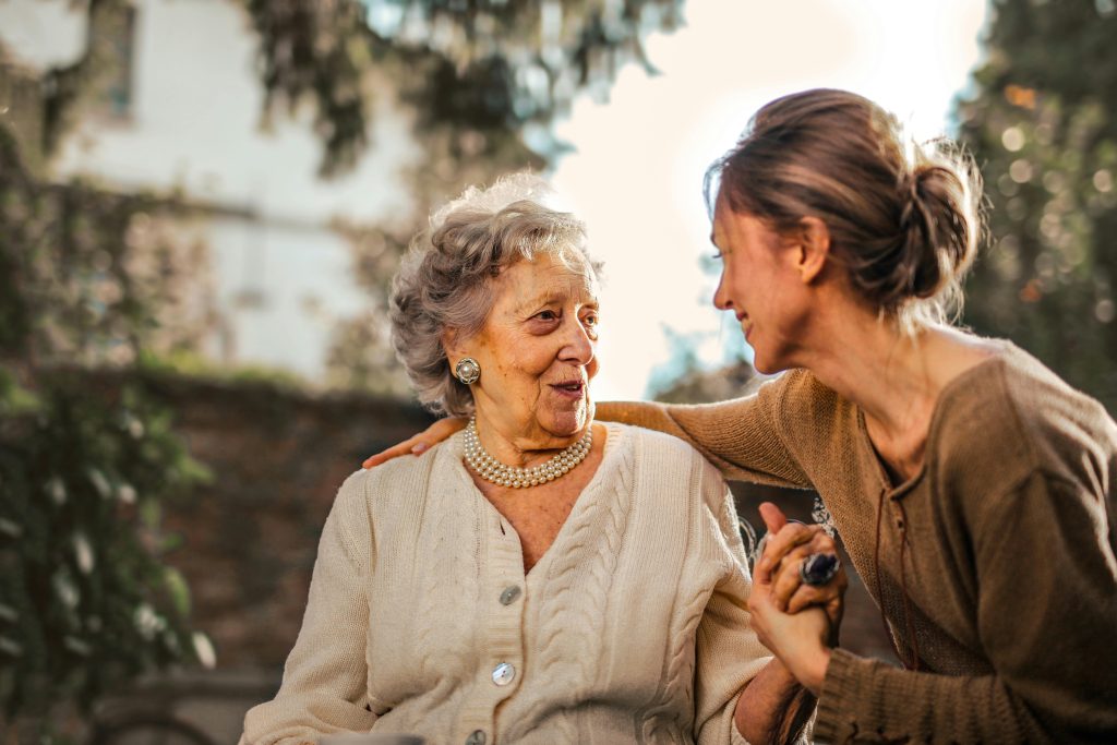 An elderly woman and her daughter smiling at each other