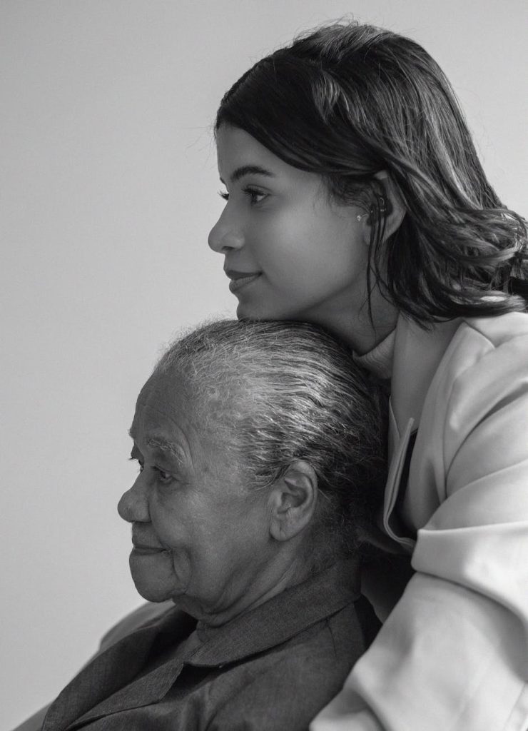 An elderly woman being hugged by her granddaughter